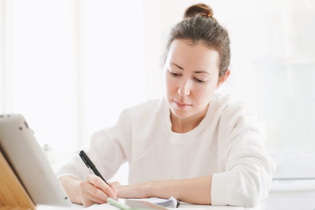 learning concept, young woman studying with a tablet, writing down the notes-6080191.jpg